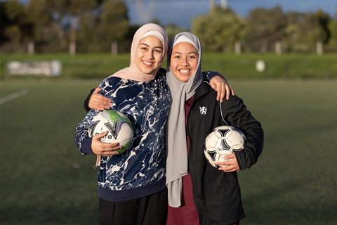 Two young girls on a soccer pitch