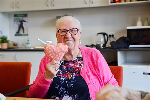 elderly lady holding up a fabric heart