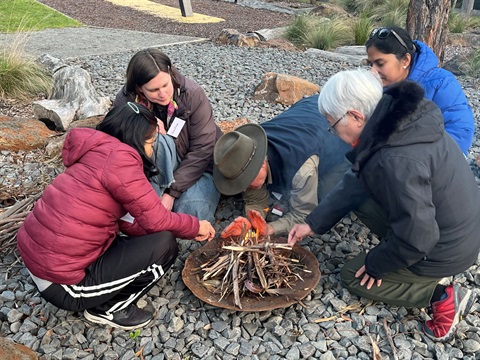 people learning to light camp fire