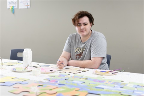 Youth community art project Jay aspiring support worker paints a spotted marsh frog for public mural.