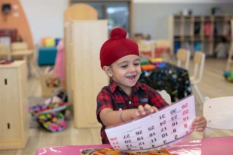 A child is sitting happily in a kindergarten classroom.