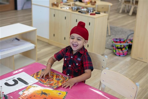 A child is sitting happily in a kindergarten classroom.