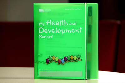 A green book with the words My Health and Development and a colourful caterpillar on the cover.