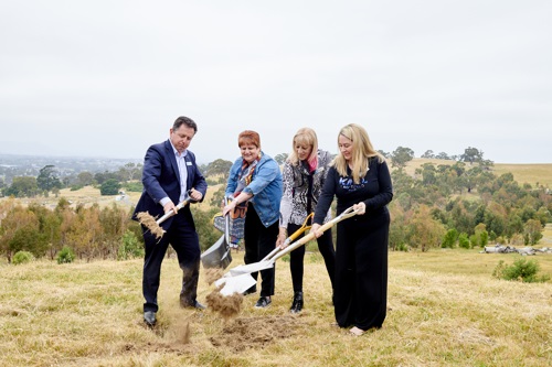 Four people hold shovels and turn a sod of earth to mark the start of works.