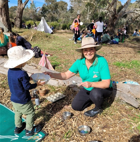 A young child learns about nature through sensory play, guided by a caring instructor.